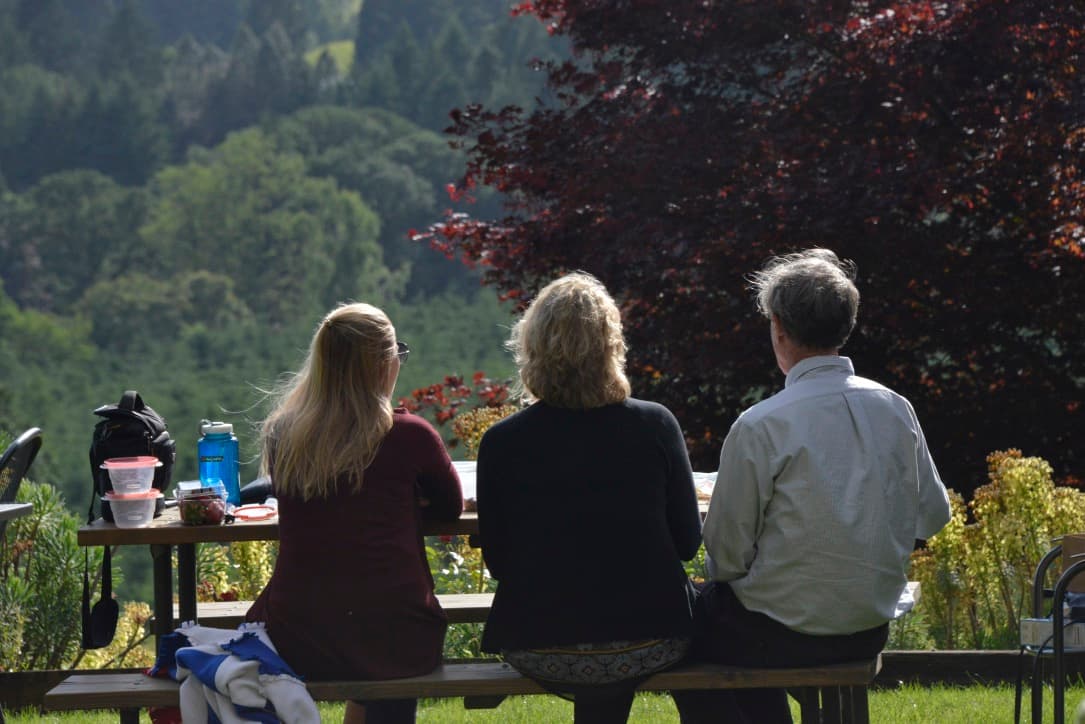 Outdoor retreat setting with participants collaborating at a picnic table in the Oregon hills